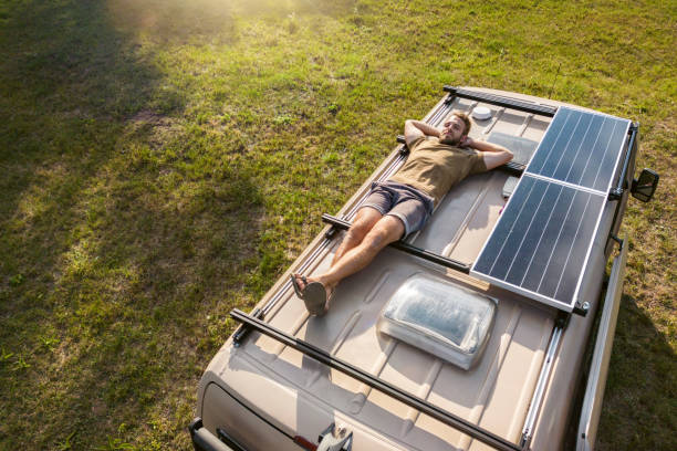 A man laying on top of an RV with solar panels